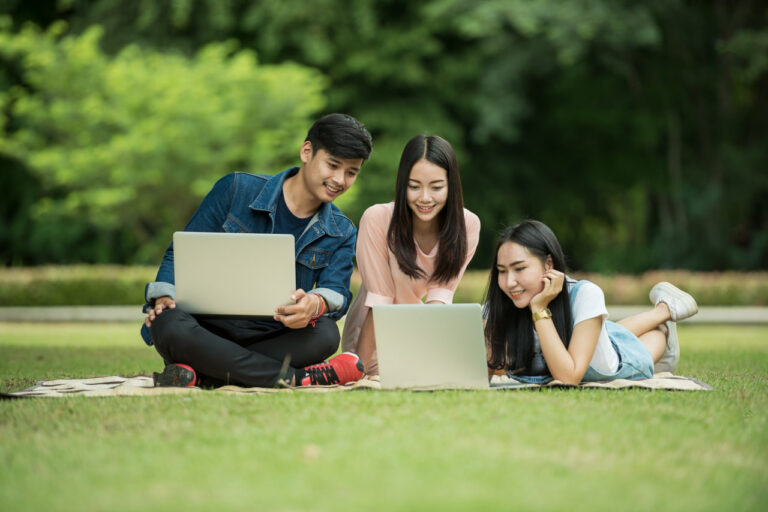 Estudiantes utilizando portátiles al aire libre mientras acceden a formación online en plataforma educativa digital