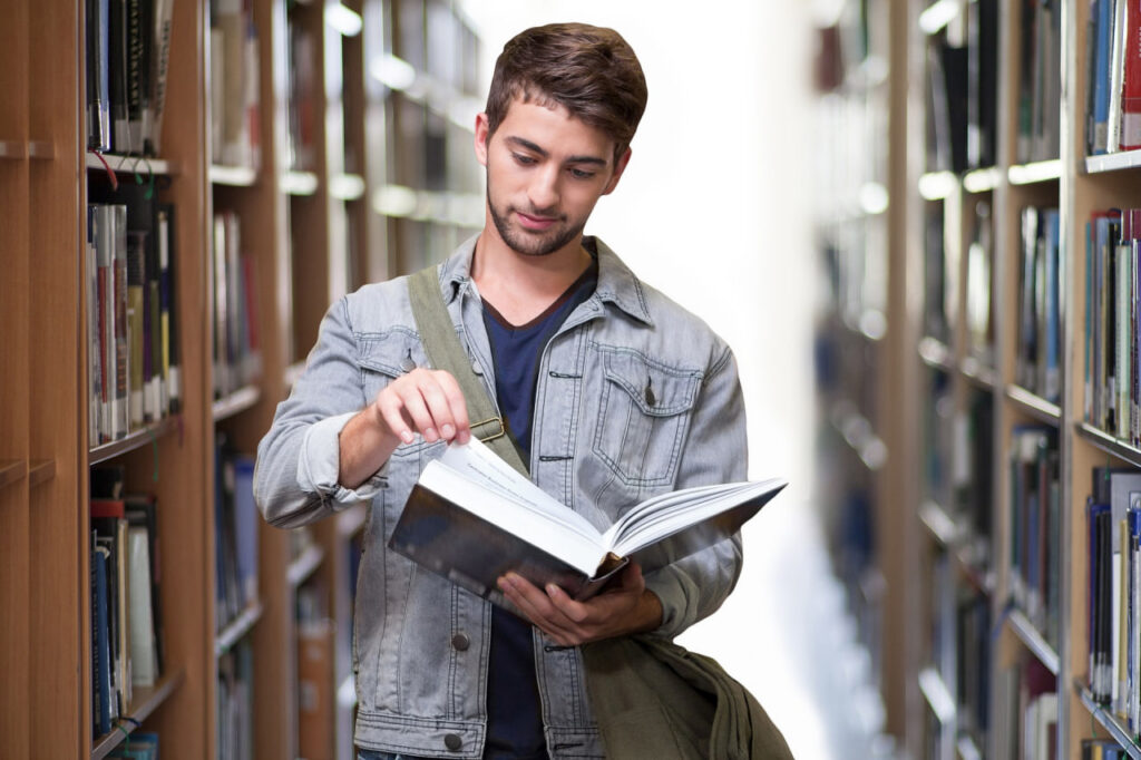 Estudiante consultando un libro en una biblioteca en un entorno de aprendizaje y formación educativa